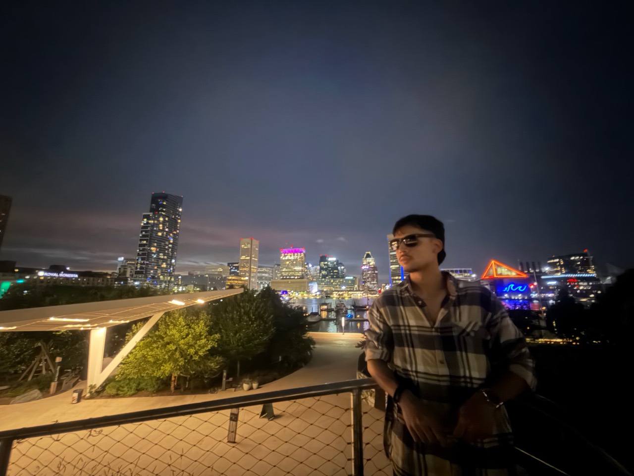 Swopnab wearing sunglasses with a city skyline at night